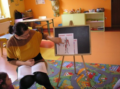 kobieta demonstruje szkielet anatomiczny na tablicy w przedszkolu
