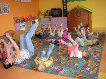 dzieci bawiące się z opiekunką na dywanie w przedszkolu