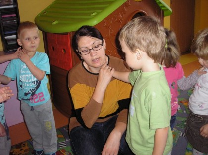 dzieci bawiące się z opiekunką w tle zabawkowy domek