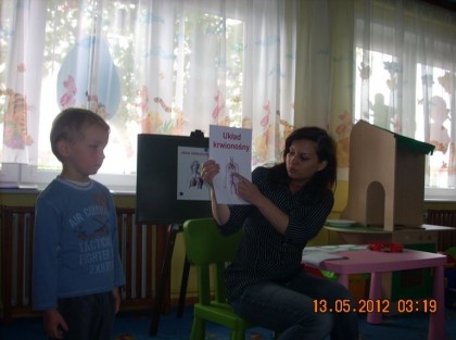 opiekunka z chłopcem demonstrują obrazki reszcie dzieci