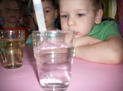 dzieci przyglądające się doświadczeniu ze szklanką wody