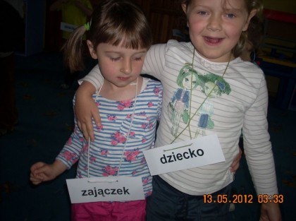 dziewczynki z kartkami na szyi bawią się w przedszkolu
