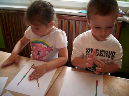 dwójka dzieci przy stole maluje na kartkach