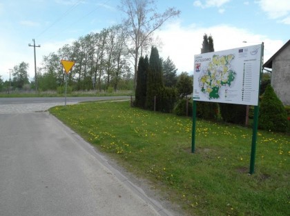 tablica informacyjna gminy ustawiona obok drogi