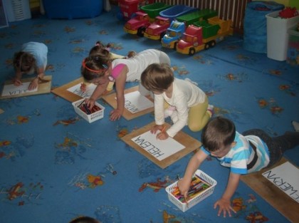 dzieci rysujące obrazki na dywanie w przedszkolu
