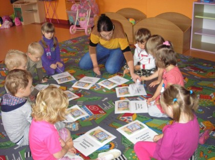 przedszkolanka z dziećmi ogląda ilustracje