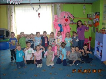 dzieci wraz z przedszkolanką pozują do zdjęcia z dużym różowym królikiem