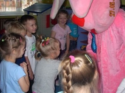 dzieci bawiące się z dużym różowym królikiem