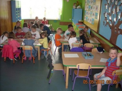 grupa dzieci siedząca przy stolikach w przedszkolu
