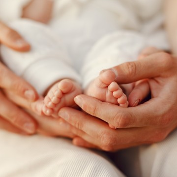 nóżki dziecka w dłoniach matki