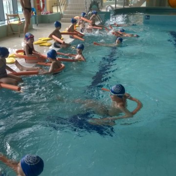 grupa dzieci uczy się pływać w basenie