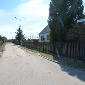 droga asfaltowa obok posesji prywatnej z domem mieszkalnym