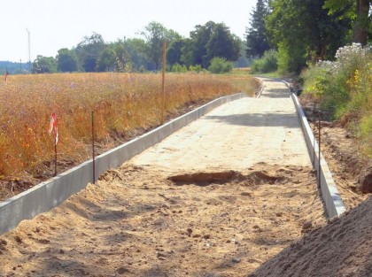 Zdjęcie przedstawiające ułożone krawężniki pomiędzy nimi ubijanie piasku