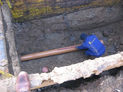 Kładzenie rur sieci kanalizacyjnej przez pracownika budowlanego w wykopie zdjęcie z góry