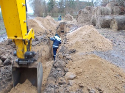 Prace ziemne pod sieć kanalizacyjną, na pierwszym planie kopiąca łyszka i pracownik budowlany