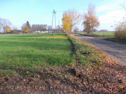 Zdjęcie drogi przed modernizacją, w oddali gospodarstwo rolne