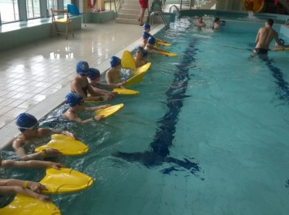 grupa dzieci z deskami do nauki pływania w basenie