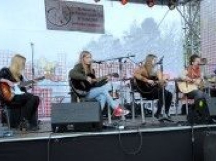 młode kobiety grające na gitarze podczas pikniku na scenie