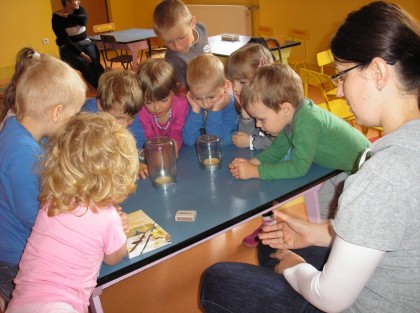 dzieci wpatrujące się w słoiki stojące na stole